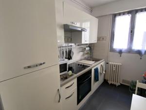 Biała kuchnia ze zlewem i kuchenką w obiekcie Le P'tit Gris w mieście Rochefort