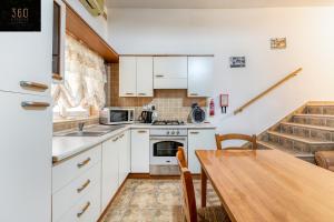 een keuken met witte kasten en een houten tafel bij Lovely, comfy 2BR home with comfy sofa w/WIFI & AC by 360 Estates in St Paul's Bay