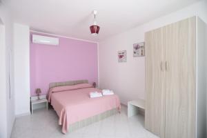 um quarto com uma cama rosa e um armário em B&B Saracinello em Praia a Mare