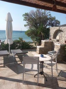 un patio con mesa, sillas y sombrilla en Studios Margarita, en Platis Yialos Sifnos