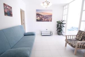 ein Wohnzimmer mit einem blauen Sofa und einem Stuhl in der Unterkunft ApartamentoSolPraia - Cruzeiro in Portimão