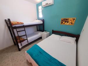 um pequeno quarto com uma cama e um beliche em Villa Coelho - Pousada a 5 minutos de Guarajuba em Camaçari