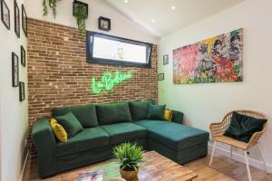 uma sala de estar com um sofá verde e uma parede de tijolos em Bel appart rénové - la bohème em Hyères