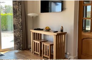 uma pequena mesa de madeira com uma televisão na parede em The Garden Room at Amelia Cottage em Whiting Bay