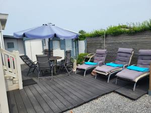 a deck with chairs and a table and an umbrella at NV 206 - Beach Resort Nieuwvliet Bad in Nieuwvliet