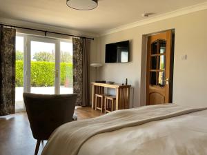 una camera con un letto, una sedia e una TV di The Garden Room at Amelia Cottage a Whiting Bay