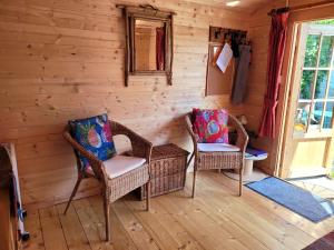 a room with two wicker chairs and a window at Tan y coed's Rosemary Cabin in Conwy
