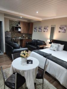 ein Hotelzimmer mit einem Bett, einem Tisch und Stühlen in der Unterkunft Villa Rose Cottages in Bloemfontein