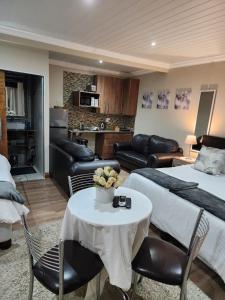 Habitación de hotel con cama, mesa y sillas en Villa Rose Cottages en Bloemfontein