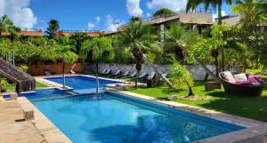 a swimming pool in front of a resort with palm trees at Apartamento com Jacuzzi na Praia de Pipa. in Pipa
