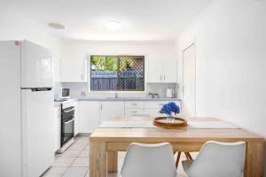 a kitchen with a wooden table and white cabinets at Hervey Bay Shelly Beach Stay ,Pet Friendly 300m to beach in Torquay