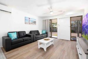 a living room with a black couch and a table at Hervey Bay Shelly Beach Stay ,Pet Friendly 300m to beach in Torquay