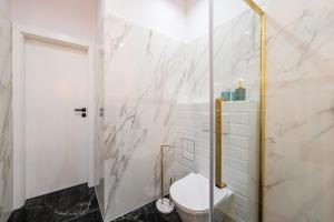 a bathroom with a toilet and a marble wall at LuxuryApartamentsIjordC in Katowice