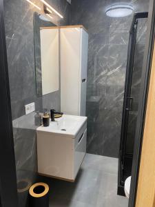 La salle de bains est pourvue d'un lavabo blanc et d'une douche. dans l'établissement Apartament Spokojna Przystań, à Rowy