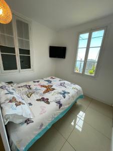 1 Schlafzimmer mit einem Bett mit einer Bettdecke und 2 Fenstern in der Unterkunft Maison avec jardin, vue mer aux portes de Monaco in Beausoleil