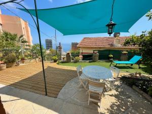 eine Terrasse mit einem Tisch, Stühlen und einem Sonnenschirm in der Unterkunft Maison avec jardin, vue mer aux portes de Monaco in Beausoleil