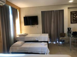 a hotel room with two beds and a flat screen tv at Savassi Tower Cobertura in Belo Horizonte +50 photos