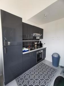 eine Küche mit schwarzen Schränken und einem Küchenteppich in der Unterkunft JOLIE MAISON DE VILLAGE in Mégrit
