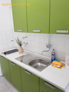 una cocina con armarios verdes y fregadero en Rosemary apartment, en Izola