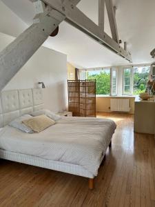 um quarto com uma grande cama branca num quarto em Suite privative dans maison de caractère em Le Faou