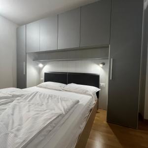 - une chambre avec un grand lit et des draps blancs dans l'établissement Trentino Apartments - San Lorenzo, à Folgaria