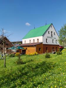 a large white and brown barn with a green roof at Penzion Špičák in Boží Dar