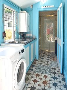 a laundry room with a washing machine and blue walls at Aqua Cottage in Combe Martin