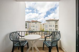 a table and two chairs on a balcony with a window at Escapadinha do Sol by Homie in Pontinhas