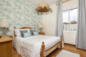 a bedroom with a bed and a large window at Escapadinha do Sol by Homie in Pontinhas