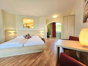 TrebesingにあるFamilienhotel Trebesingerhofのベッドとデスクが備わるホテルルームです。