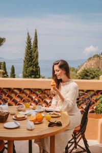 una mujer sentada en una mesa comiendo comida en Les Terrasses du Bailli, en Rayol-Canadel-sur-Mer