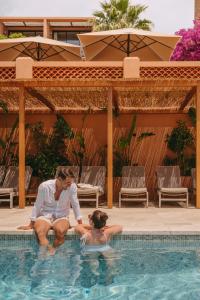 a man and woman sitting in a swimming pool at Les Terrasses du Bailli in Rayol-Canadel-sur-Mer