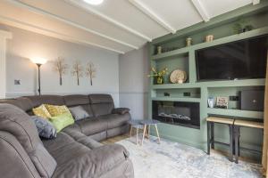 a living room with a couch and a flat screen tv at Saddlers Cottage with indoor pool, tennis court and lots more Tenby area in Saint Florence