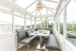 a conservatory with a table and chairs and windows at Saddlers Cottage with indoor pool, tennis court and lots more Tenby area in Saint Florence