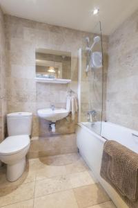 a bathroom with a toilet and a sink and a bath tub at Saddlers Cottage with indoor pool, tennis court and lots more Tenby area in Saint Florence