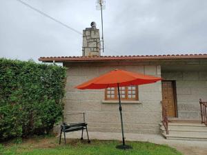 a red umbrella and a chair in front of a house at Lar a de Luis in Ribadumia