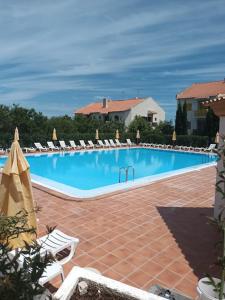a large swimming pool with lounge chairs and umbrellas at Nora Velha T1 in Tavira