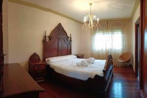 a bedroom with a large bed and a chandelier at Lar a de Luis in Ribadumia