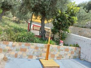 a wooden bench sitting in front of a wall at Stafylos Rooms in Stafylos