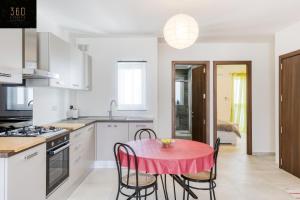 uma cozinha branca com uma mesa vermelha e cadeiras em Lovely 2BR home 2 mins away from the promenade by 360 Estates em St. Paul's Bay