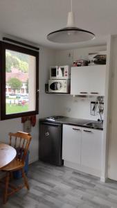 een keuken met witte kasten en een tafel en een raam bij Studio Le petit Som in Saint-Pierre-de-Chartreuse