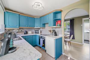 une cuisine avec des armoires bleues et une table dans l'établissement Stunning 3 bed Abode in Nuneaton- Sleeps 7, à Nuneaton