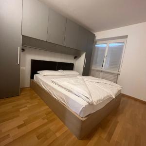 ein großes Bett in einem Schlafzimmer mit Holzboden in der Unterkunft Trentino Apartments - San Lorenzo in Folgaria