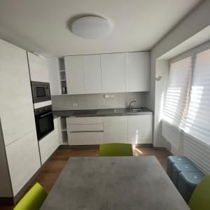 eine Küche mit weißen Schränken sowie einem Tisch und Stühlen in der Unterkunft Trentino Apartments - San Lorenzo in Folgaria