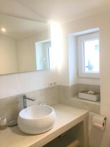 La salle de bains est pourvue d'un lavabo blanc et d'un miroir. dans l'établissement Au calme dans le centre avec terrasse et clim, à Saint-Rémy-de-Provence