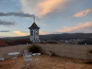 un patio con tavoli, sedie e una torre dell'orologio. di Pousada Ouro de Minas a Diamantina