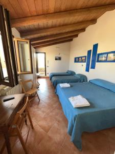a room with three beds and a table and windows at Dimora Tipica in Marsala