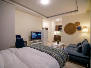 a bedroom with a bed and a couch and a tv at 46 Serviced Apartments in Amman