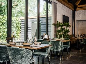 um restaurante com cadeiras verdes, mesas e janelas em Lindenhuys Logies em Sint-Oedenrode