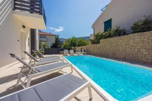 Una piscina con tumbonas al lado de un edificio. en Villa BAŠKA near the beach, en Baška